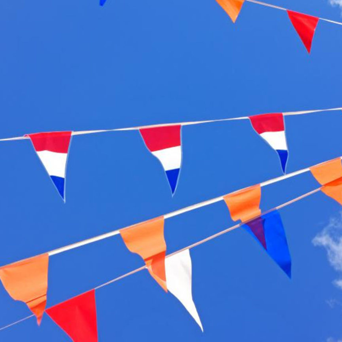 Nederlandse en oranje vlaggetjes in de blauwe lucht.